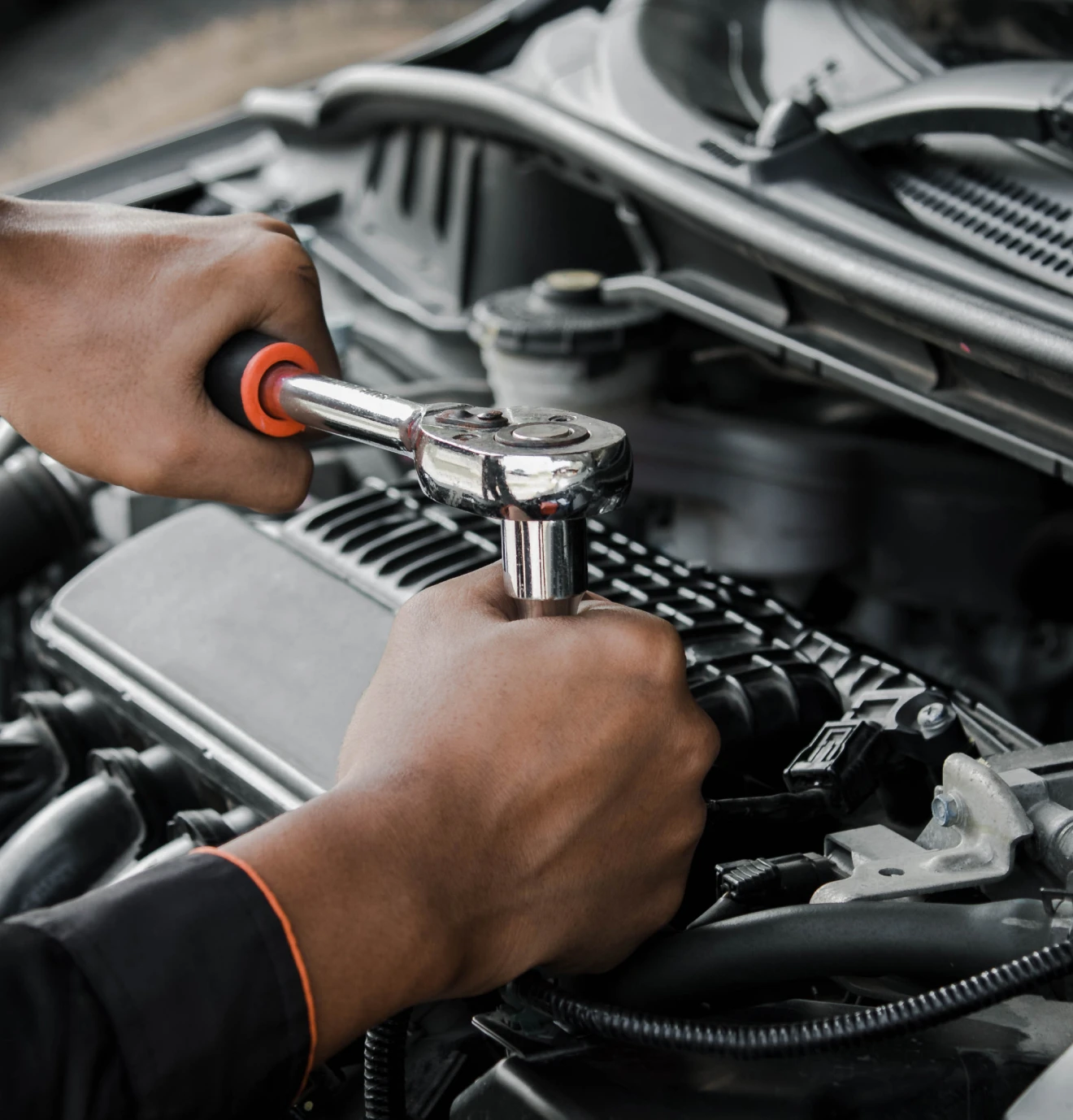Hands repairing car engine with wrench